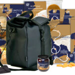 Kerstpakket met luxe zwarte rugzak gevuld met Hollandse streekproducten zoals stroopwafels, jam, noten en kaasdip.